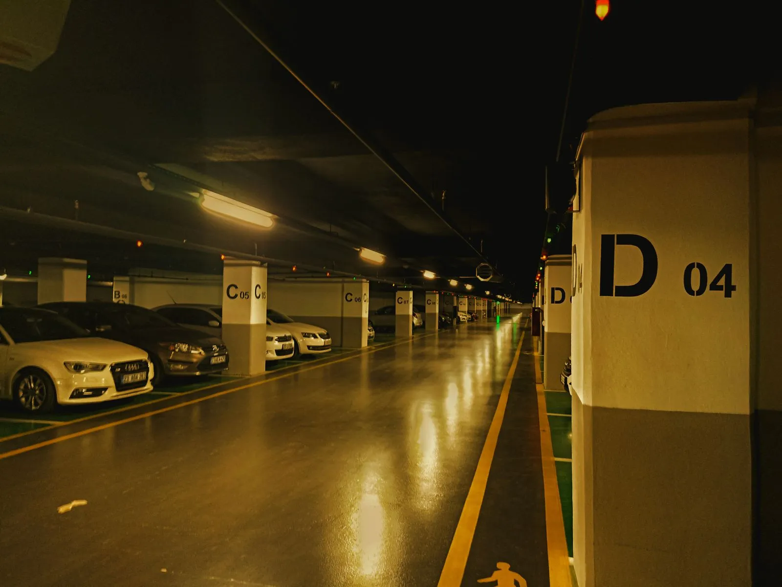 A dimly lit underground parking garage with parked cars and vacant spaces.